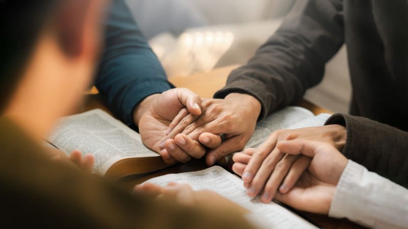 Group of Christians praying together holding hands